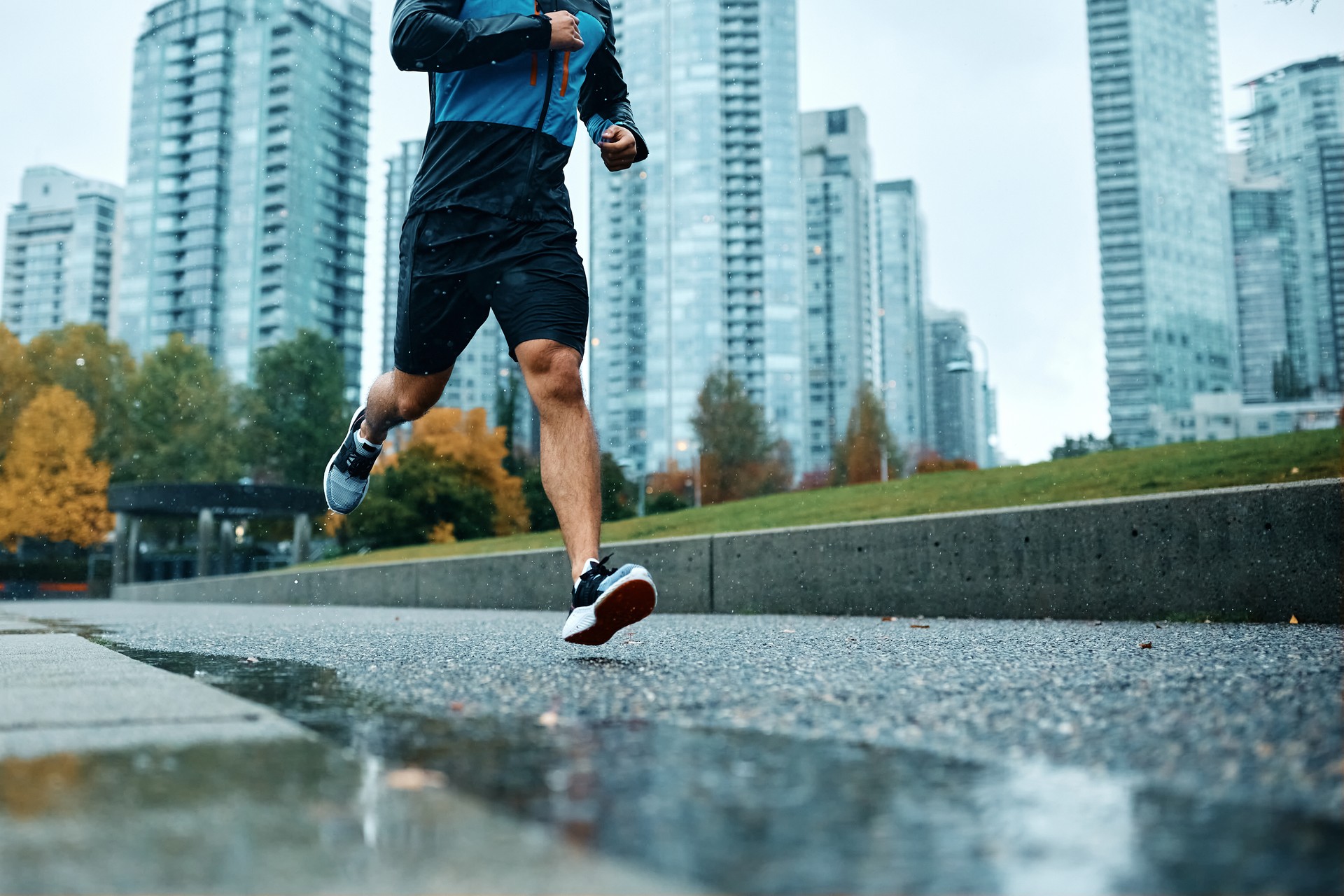 Unrecognizable athletic man running during rainy day.